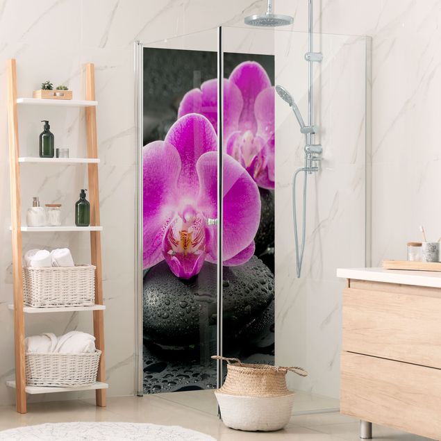 Duschrückwand Aluverbund Pinke Orchideenblüten auf Steinen mit Tropfen
